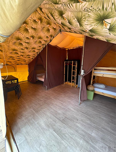 Chambre avec lits superposés de la tente lodge avec sanitaire. Hébergement insolite en Gironde au camping Montacabana à Montalivet